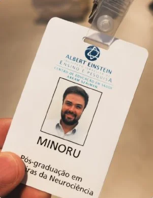 Crachá de aluno da pós-graduação em Neurociência do Instituto Israelita de Ensino e Pesquisa Albert Einstein, com a foto e o nome Minoru