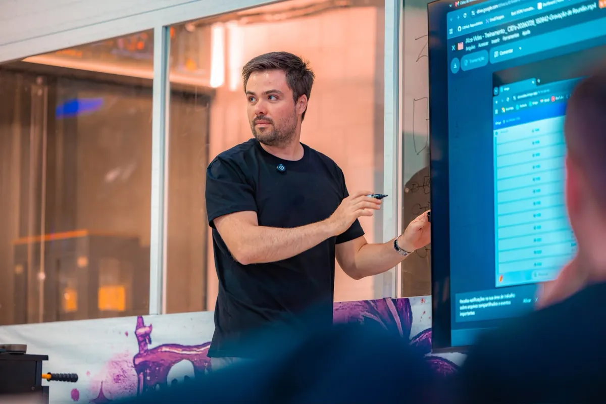 Minoru Raphael durante um treinamento, olhando para o lado e apontando para um monitor