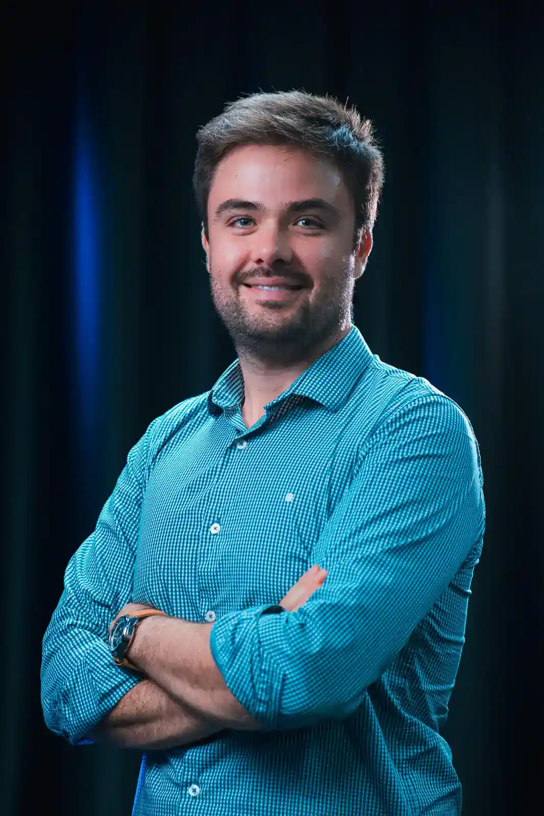 Minoru Raphael sorrindo, de braços cruzados e camisa azul quadriculada